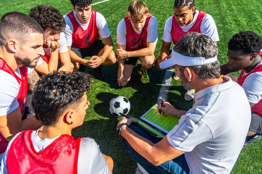 Soccer coach explaining game strategy to youth team - Powered by Adobe