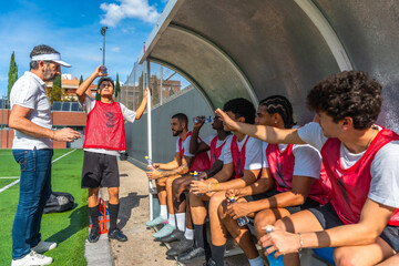 Soccer coach talking with players on sideline bench