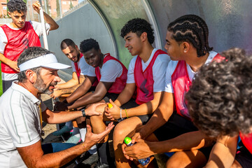 Soccer coach talking strategy with diverse young team