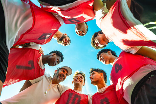 Coach and diverse team forming huddle before game