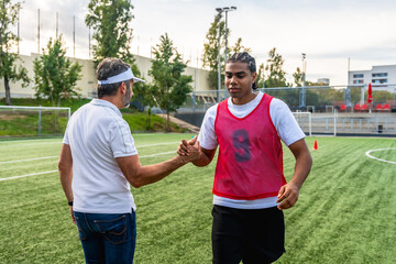 Soccer coach shaking hands with player on field