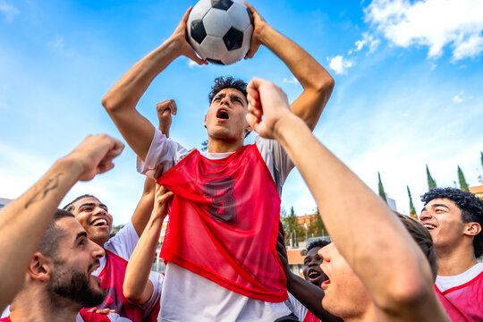 Soccer team celebrating victory holding ball up high