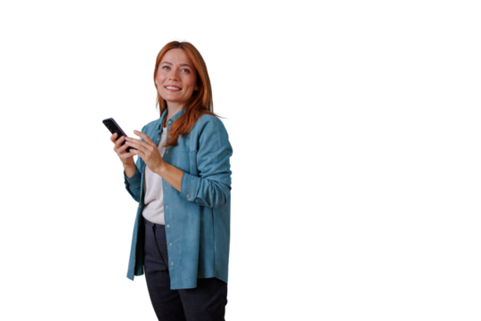 Redhead woman smiling, looking up and holding smartphone, texting and communicating on mobile device