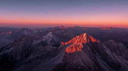 Sun rising casting long shadows over rugged mountain ridge at dawn, revealing snow-dusted peaks - Powered by Adobe