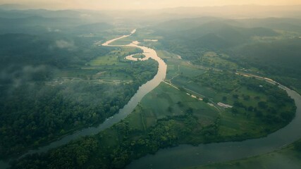 Illuminating haze revealing meandering river through forested riverbanks farmland roads and hills