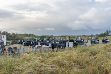 Fototapeta premium Field station with experimental setup near dunes. A research site with multiple tanks and technical units sits in a dune area. The facility studies coastal and climate effects.