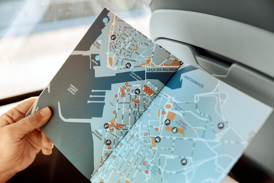 A close-up view inside a coach bus shows a female hand holding a detailed map of Porto's urban and coastal areas, illustrating travel planning on the go. Travel Europe concept.