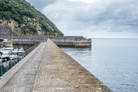 Solid Stone Breakwater and Fishing Boats in Elantxobe Harbor, sheltered by Cliffs, Cantabrian Sea