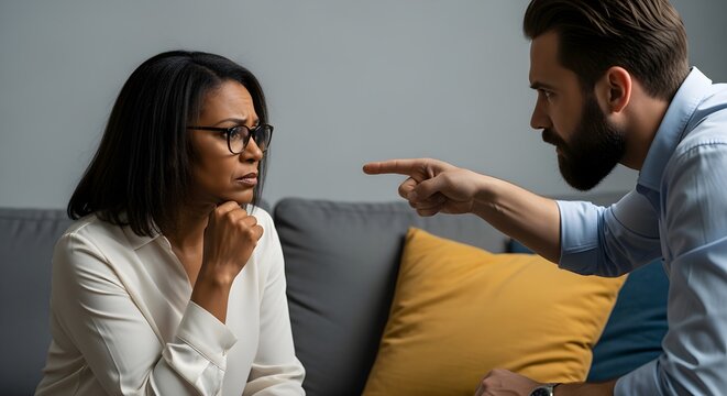 Distraught woman facing an angry man's accusation during a heated argument at home, highlighting relationship conflict and emotional distress