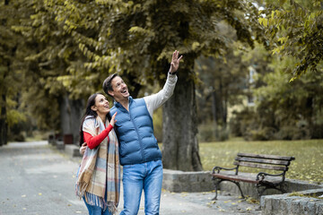 Engaged in playful banter, the couple points towards the sky, enjoying a carefree moment amidst the lush greenery of the park, filled with laughter and cherished companionship.
