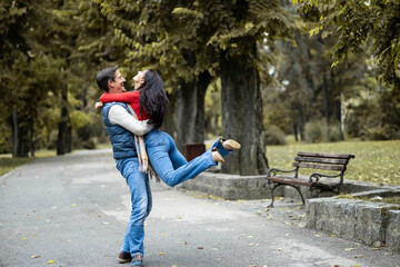Amidst the serene park, a couple dances joyfully, showcasing love and connection, as they enjoy each other's company, reflecting a moment of pure happiness and togetherness outdoors.