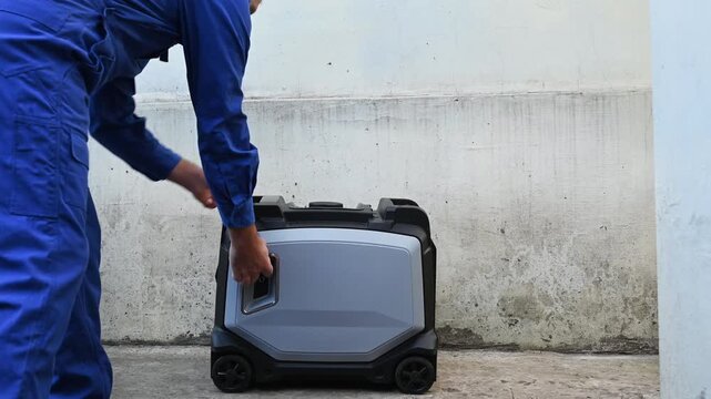 A man in overalls starts a gasoline generator, close-up of his hand