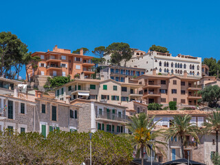 Obraz premium Port de Soller, Mallorca hillside town with colorful real estate buildings, green shutters, and palm trees under a clear blue sky, Majorca