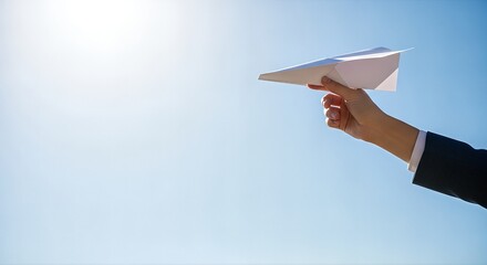 Hand launching paper airplane into clear blue sky.