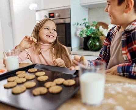 Portret of brother and sister having fun together eating breakfast in kitchen