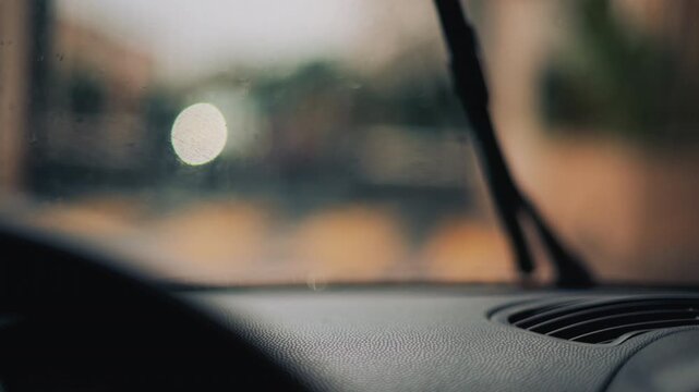 View from inside a car driving in the rain, wiping the drops off the windshield