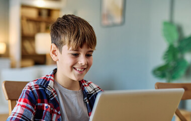 Portrait of teenage boy using tablet or laptop computer at home. Teenage boy attending to online school class