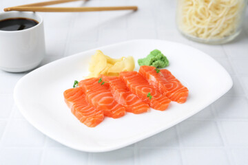 Fresh salmon sashimi with microgreens, wasabi, ginger and soy sauce on light tiled table, closeup