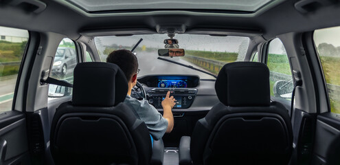 Driver uses touchscreen in rain. Tech focused ride.
