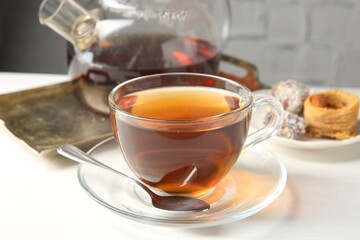 Tasty tea in glass cup, teapot and Turkish desserts on white table against grey textured background, closeup