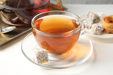 Tasty tea in glass cup and Turkish dessert on white table, closeup
