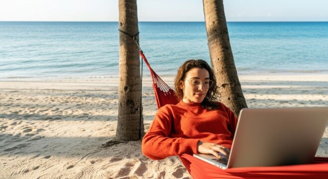 Young woman working remotely on laptop in a hammock at a tropical beach, enjoying digital nomad lifestyle and ocean views.