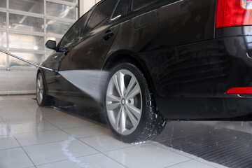 Fototapeta premium Washing auto with high pressure water jet at car wash, closeup