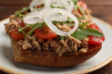 Delicious bruschettas with tuna, tomatoes, onion and arugula on table, closeup
