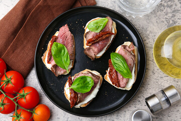 Bruschettas with roast beef served on grey table, flat lay