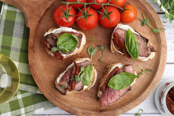 Bruschettas with roast beef served on white wooden table, flat lay