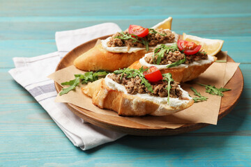 Delicious bruschettas with tuna, cream cheese and tomatoes on light blue wooden table, closeup