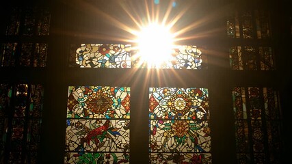Starting sunbeam piercing stained glass in chapel, brightening floral mandalas and bird motif - Powered by Adobe