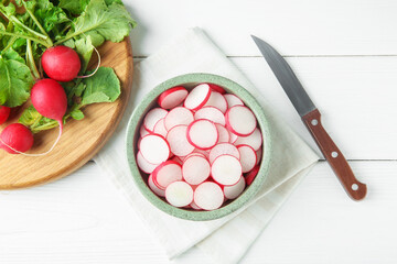 Fresh ripe radishes and knife on white wooden table, flat lay