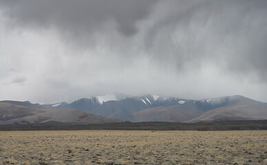 Thunderclouds and rain coming from snowy North Chuisky Ridge over the steppe