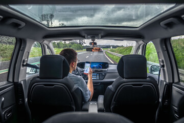 Driver using smartphone on rainy highway. Navigation on the move.