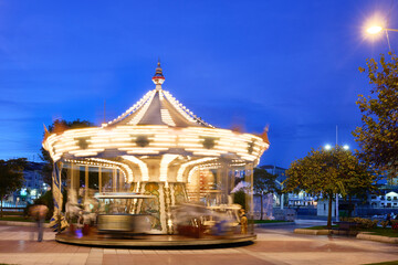 Illuminated carousel spinning a vivid light show at dusk © Juanma