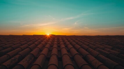 Rising sun casting warm glow across terracotta rooftop at dawn, illuminating ridge and wispy clouds - Powered by Adobe
