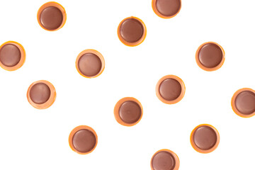 Background with caramel and chocolate sweets with hazelnut in it very similar to Toffifee in the lines next to each other separated on the white background.