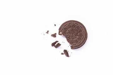 Crushed chocolate cookie with vanilla cream in the middle of cookies with crumbs and small pieces of cookie all around separated on the white background.