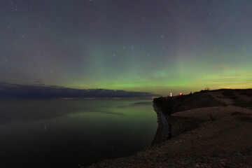 Stunning green Northern Lights (Aurora Borealis) glow in the starry sky over the Baltic Sea and Paldiski cliffs in Estonia.