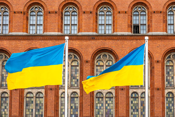 Ukrainian flags against historic brick facade. Symbol of strength and dignity.
