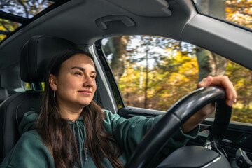 Smiling woman driving car in nature. Inspiring journey.