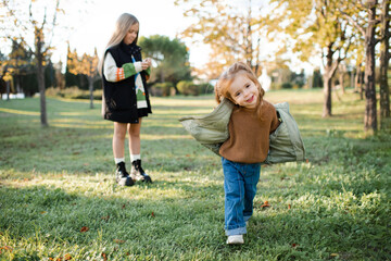 Funny smiling child girls having un in park over autumn nature background. Childhood.