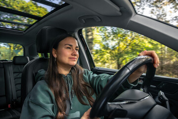 Woman driving car on forest road. Inspired road trip.