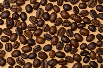 Obraz premium A closeup overhead view of roasted coffee beans scattered across a textured surface, showcasing their rich brown color and varied shapes