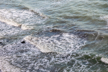 Foamy sea waves on a rocky shore. Motion and texture of water.