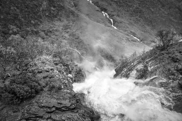 Dynamic waterfall in a rocky autumn landscape with bubbling water. Black, white