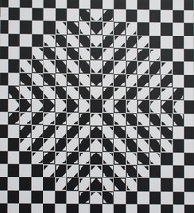 Abstract geometric optical illusion featuring a black and white checkered pattern with layered triangular shapes forming a star-like center. strong visual depth and dynamic symmetry effect.