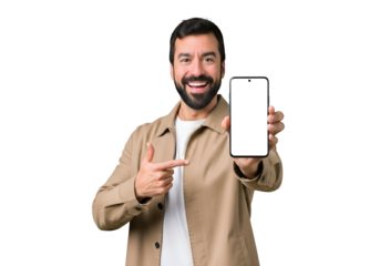 Smiling bearded man in beige coat showing a smartphone with a blank white screen and pointing at it, perfect for app promotion or digital content, isolated on transparent background.