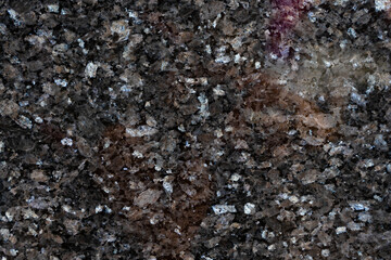 Textured close-up of a dark granite surface showcasing natural patterns and mineral variations under soft lighting